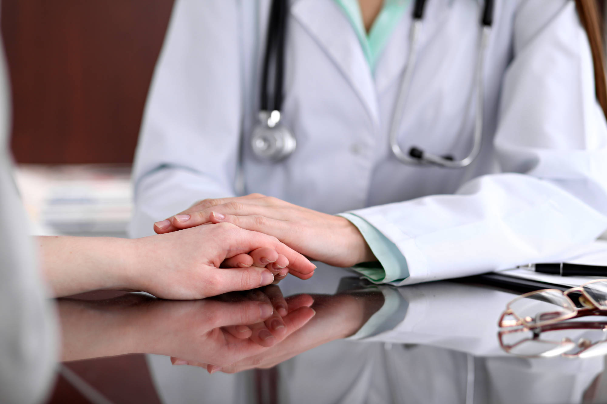 A clinician resting a reassuring hand over a patient's hands